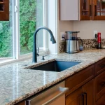 A granite kitchen sink surrounded by wood cabinets