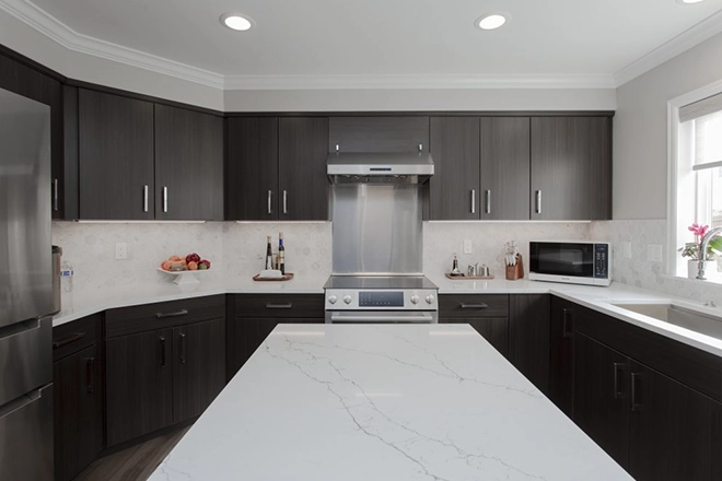Kitchen with the correct kitchen walkway spacing and dark slab cabinets and stone kitchen island